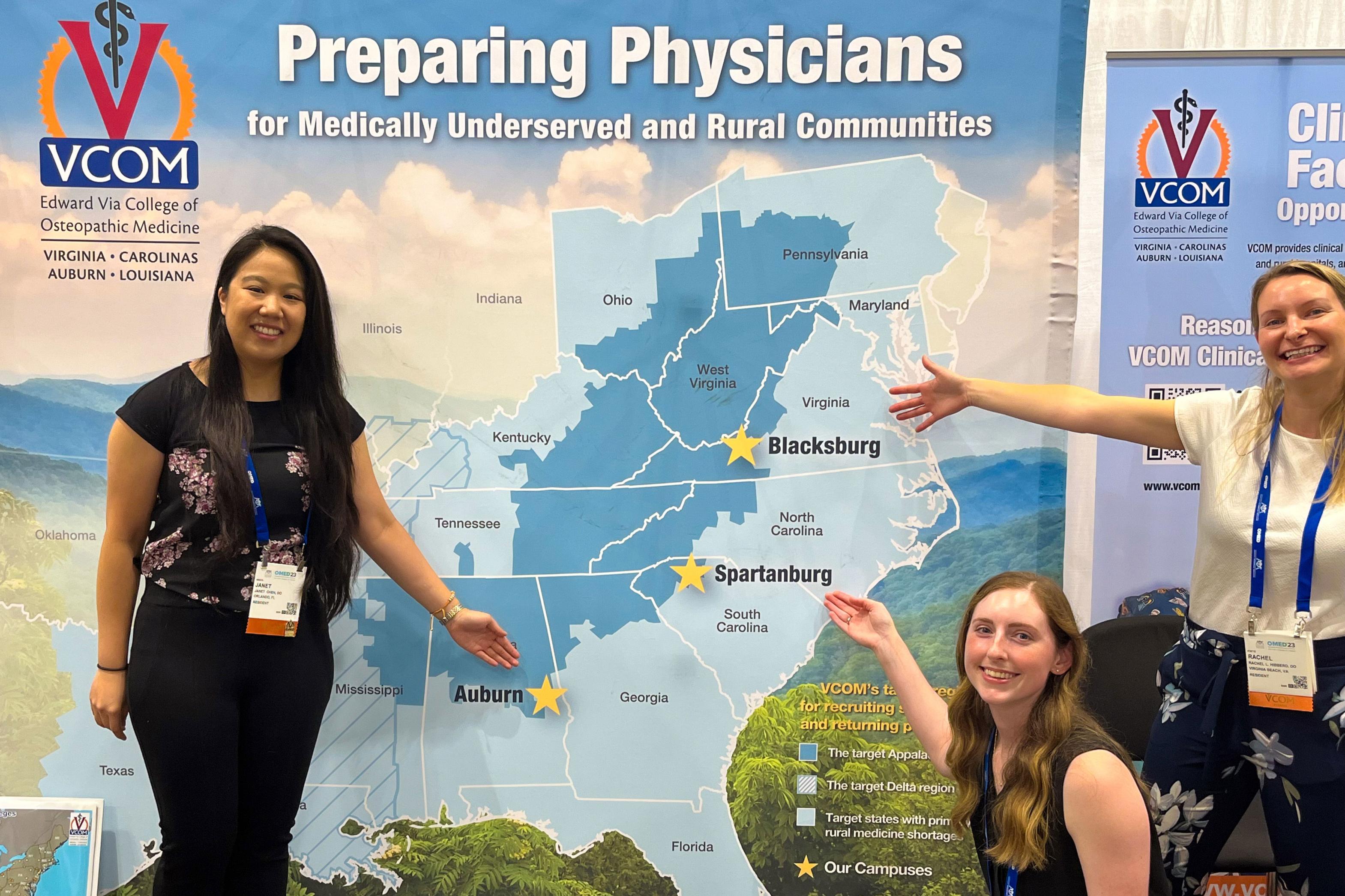 VCOM students posing in front of a map of VCOM medical school locations