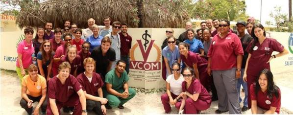 Amar and Sonul posing with other VCOM students in front of a VCOM clinic on a mission trip