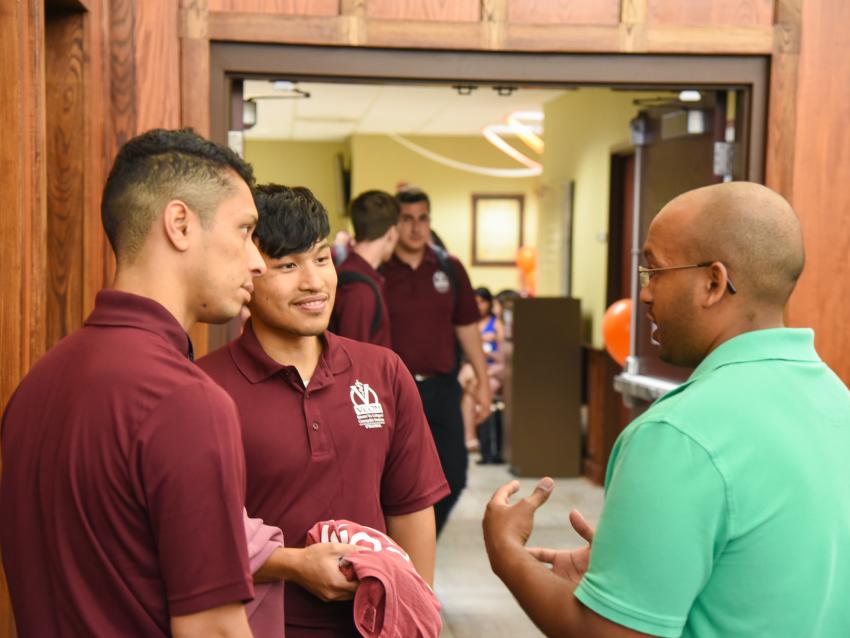 instructor speaks with new students outside classroom