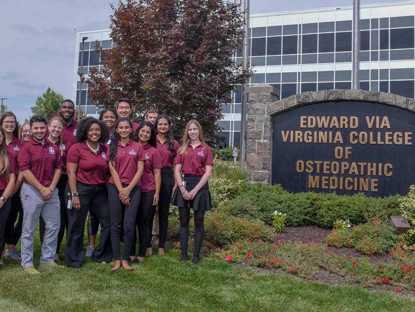 VCOM students stand beside the virginia campus sign