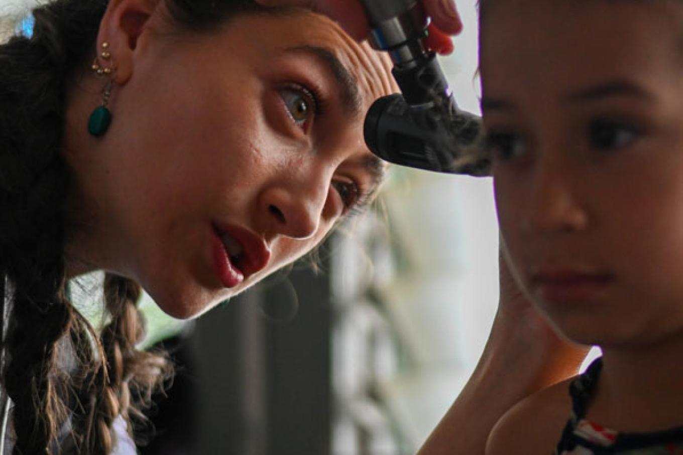 VCOM student in Honduras holding otoscope to a child's ear