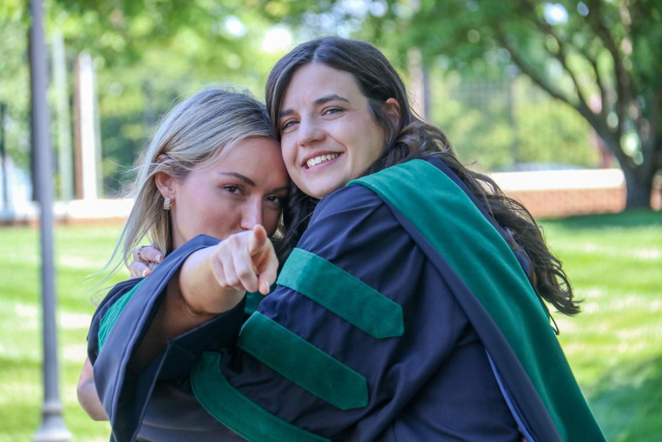 Two VCOM-Carolinas class of 2026 graduates in regalia hugging and smiling