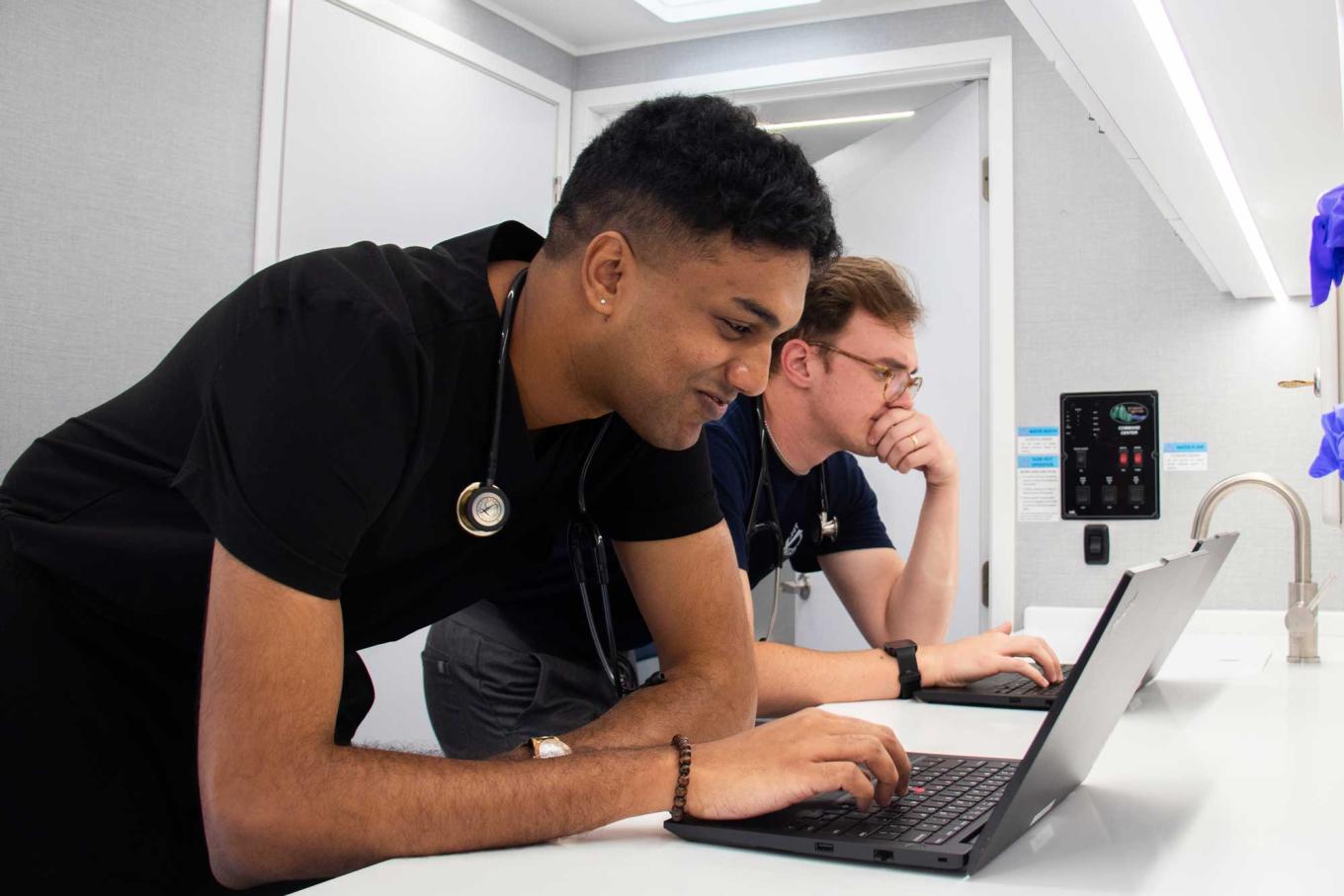Two VCOM-Carolinas students working on laptops