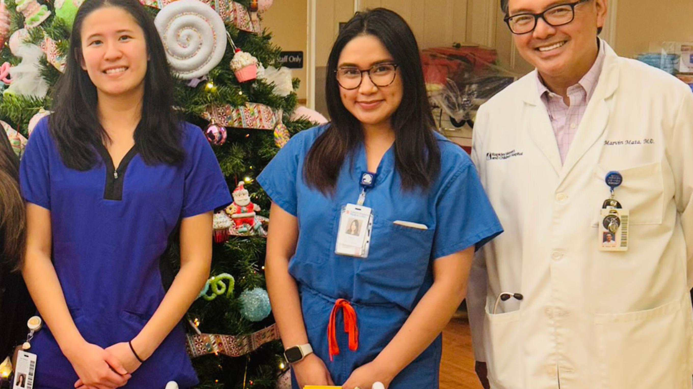 Ahmira Manalac standing with peers in front of a Christmas tree