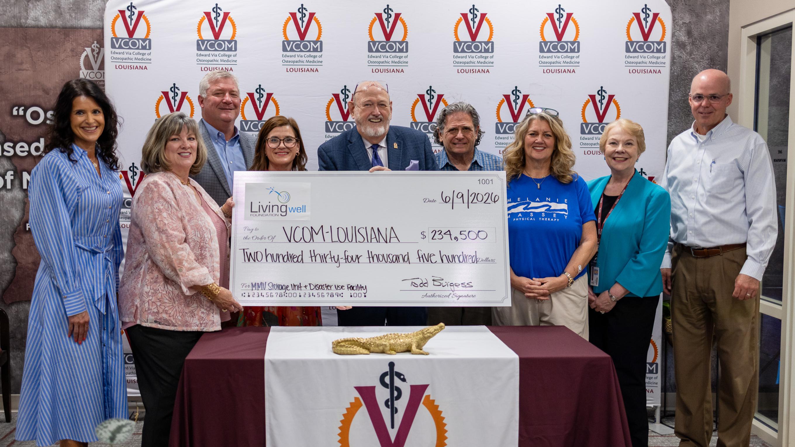 Large group holding an oversized check at VCOM-Louisiana