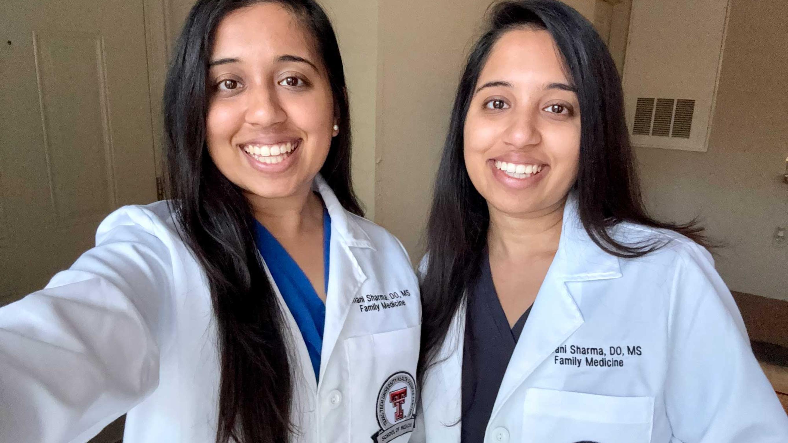 Drs. Ishani and Shivani Sharma in whitecoats smiling
