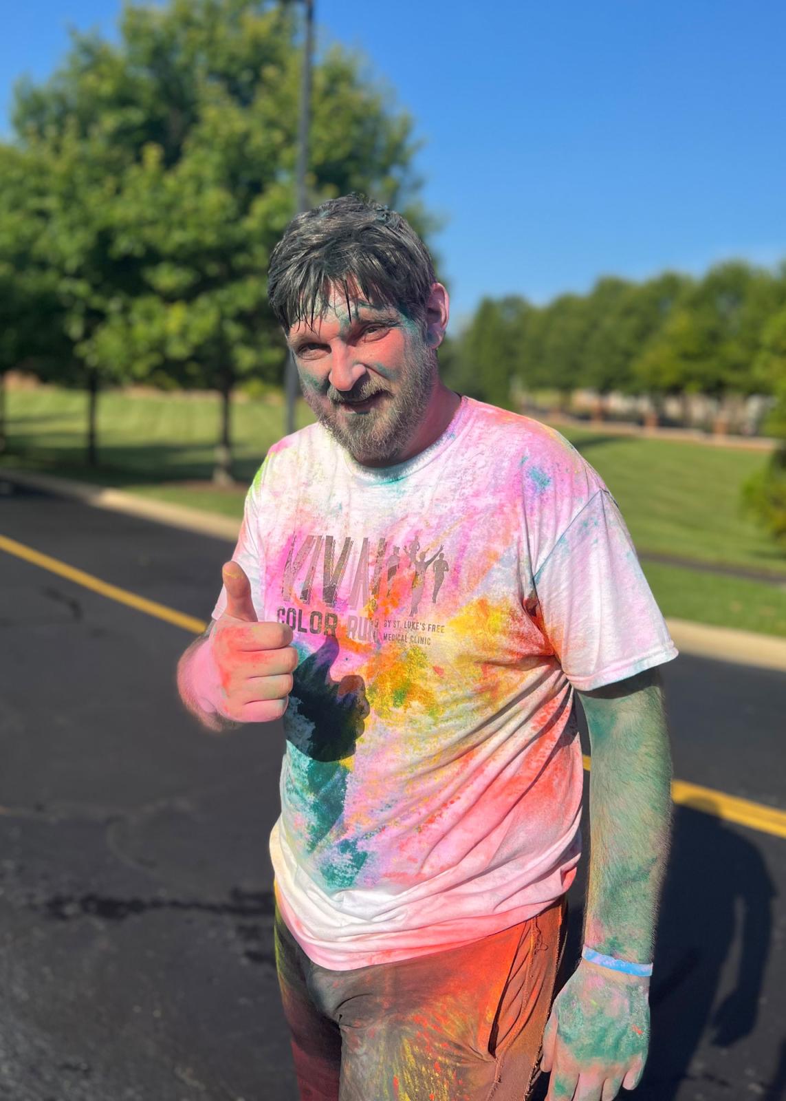 Runner with thumbs up covered in color