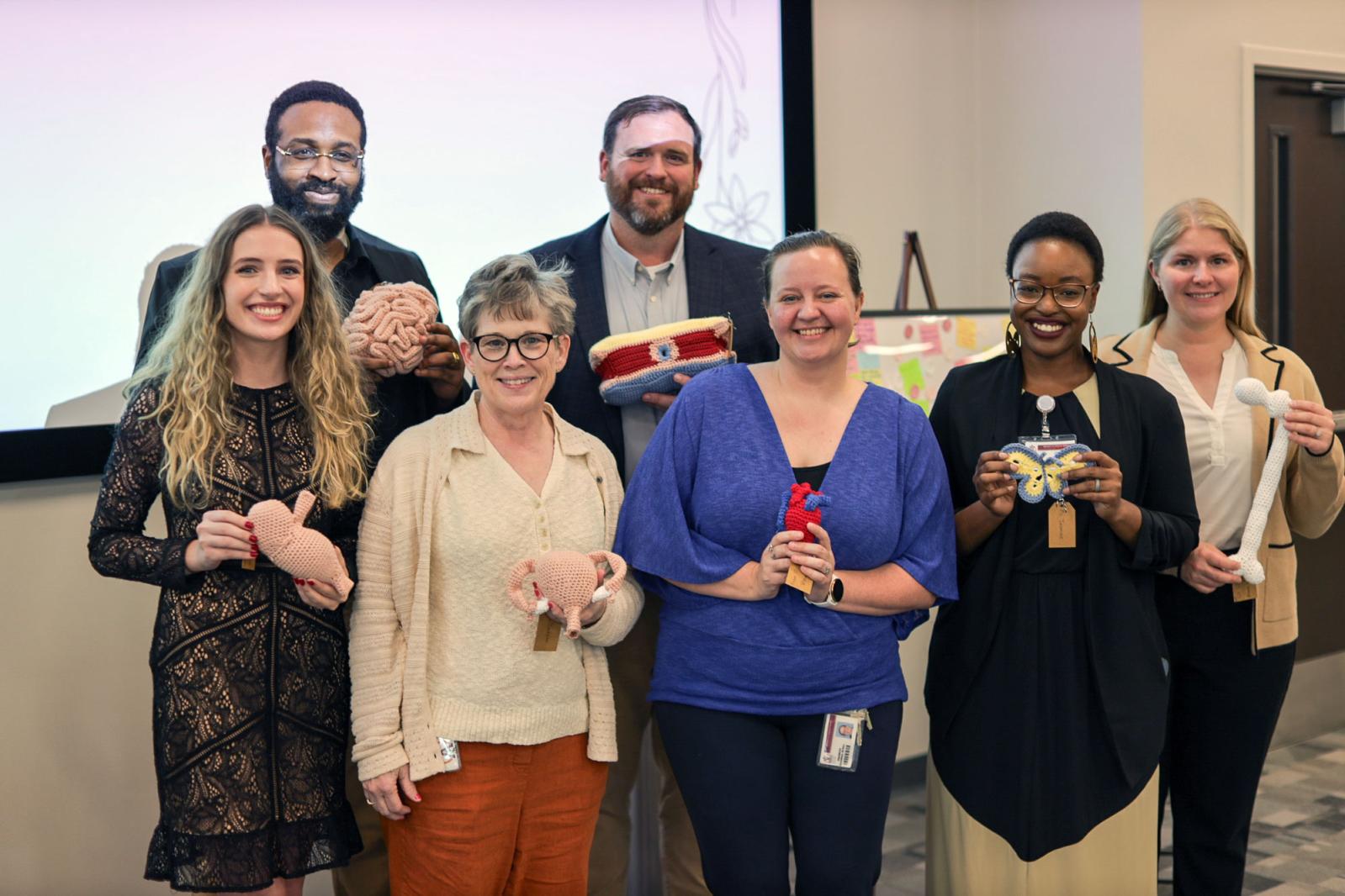 Students and faculty posing with crocheted items