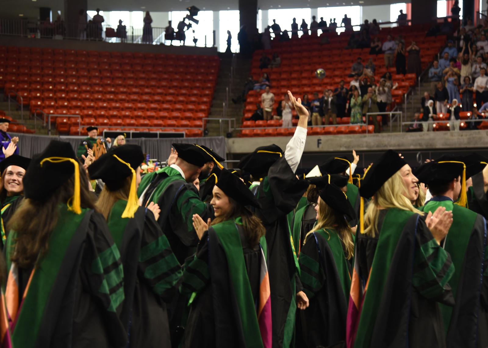VCOM class of 2025 graduates in a crowd with one person raising their hand