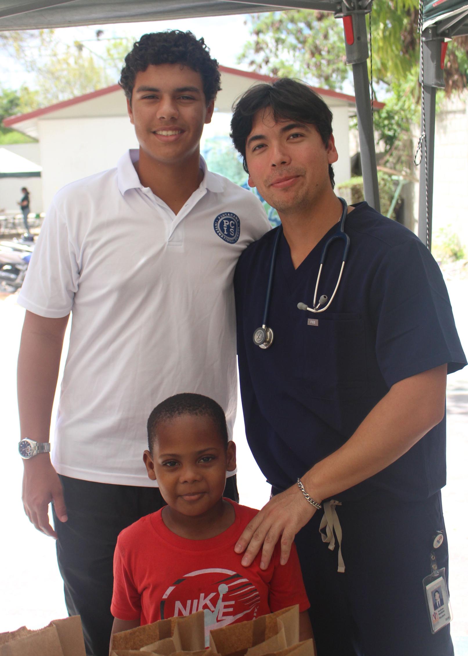 Medical student standing with a man and young boy smiling
