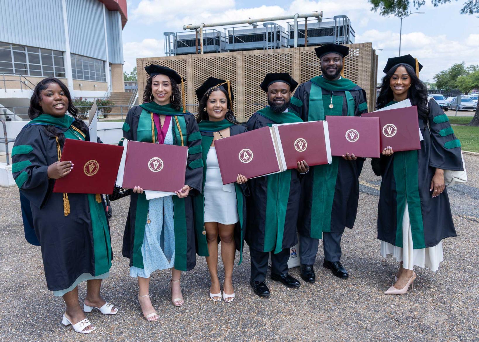 VCOM Louisiana class of 2026 graduates holding their diplomas