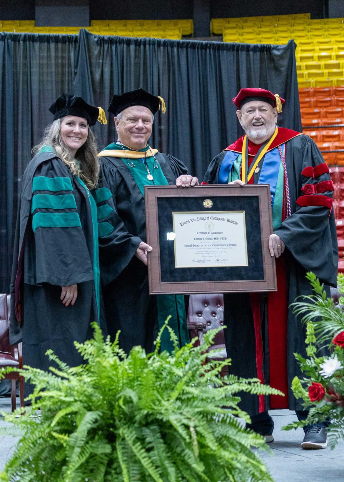 Dean and speaker for the VCOM Louisiana class of 2026 graduation standing on stage in front of a diploma smiling