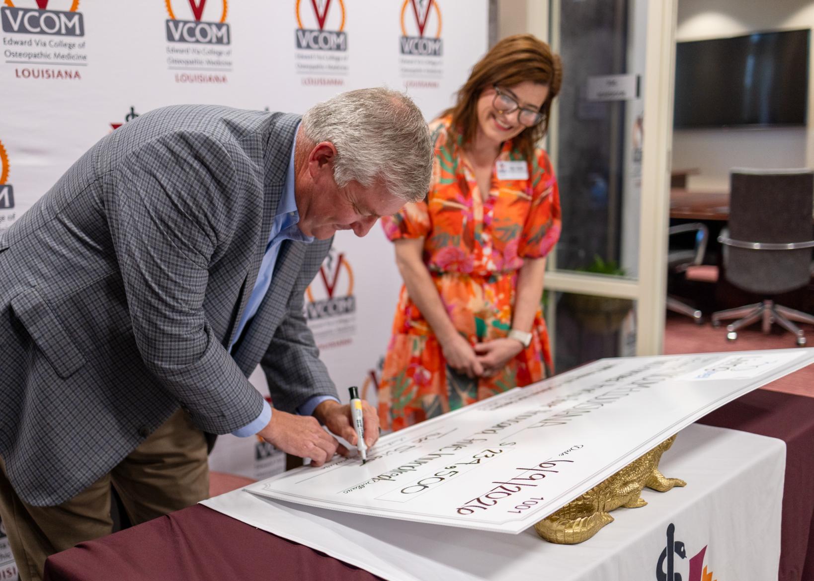 Todd Burgess, of Living Well Foundation, signing the oversized check