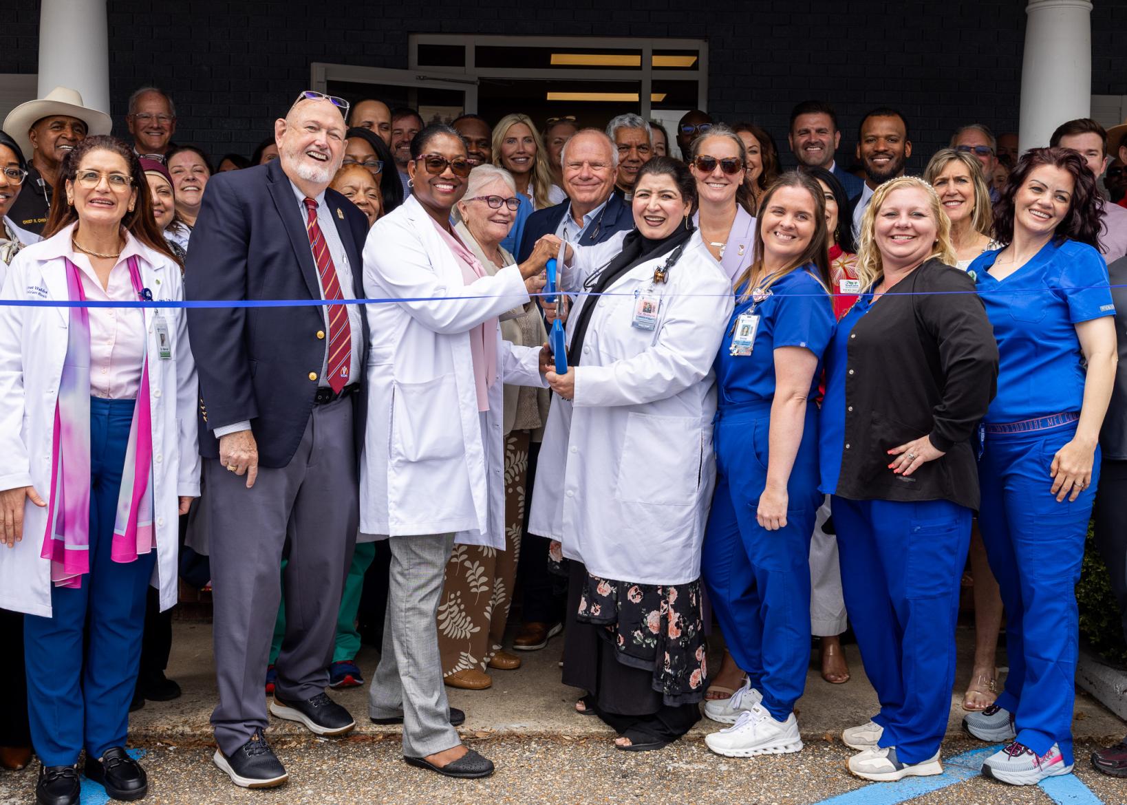 Large group smiling while cutting a ribbon