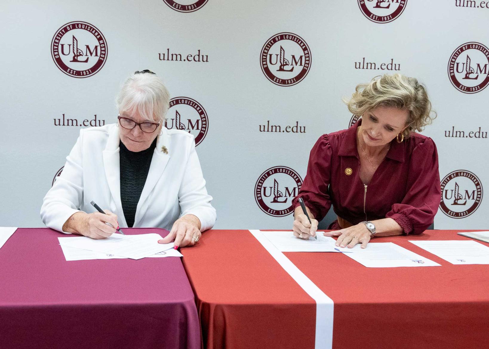 Dixie Tooke-Rawlins and Carrie L. Castille signing agreement at a table