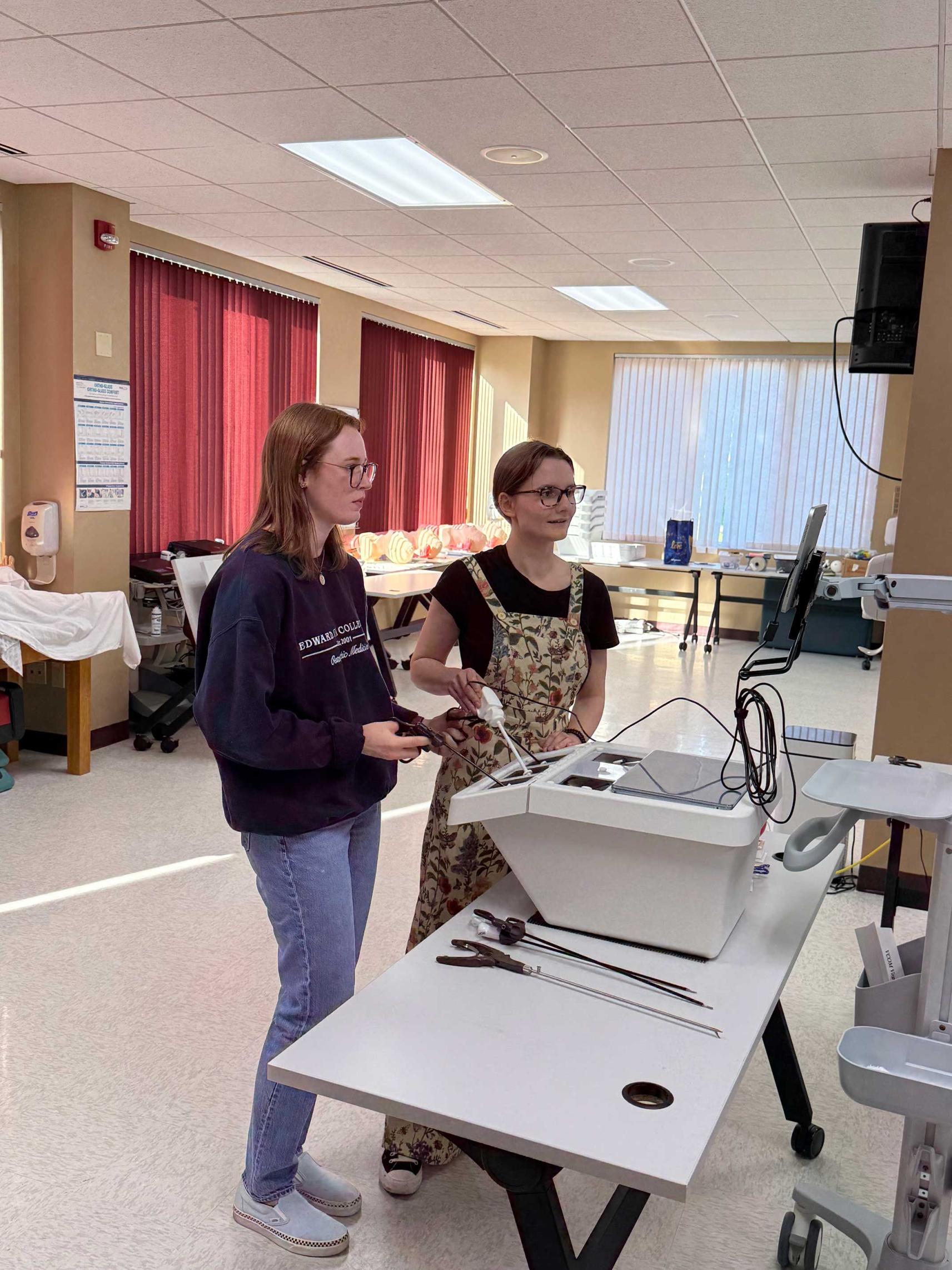 Two students in a classroom working with laparoscopic trainer
