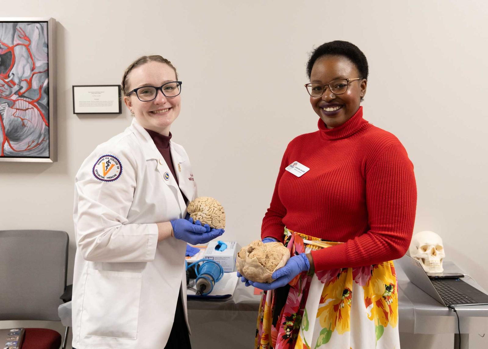 Jasmine Belton and a medical student each holding a human brain.