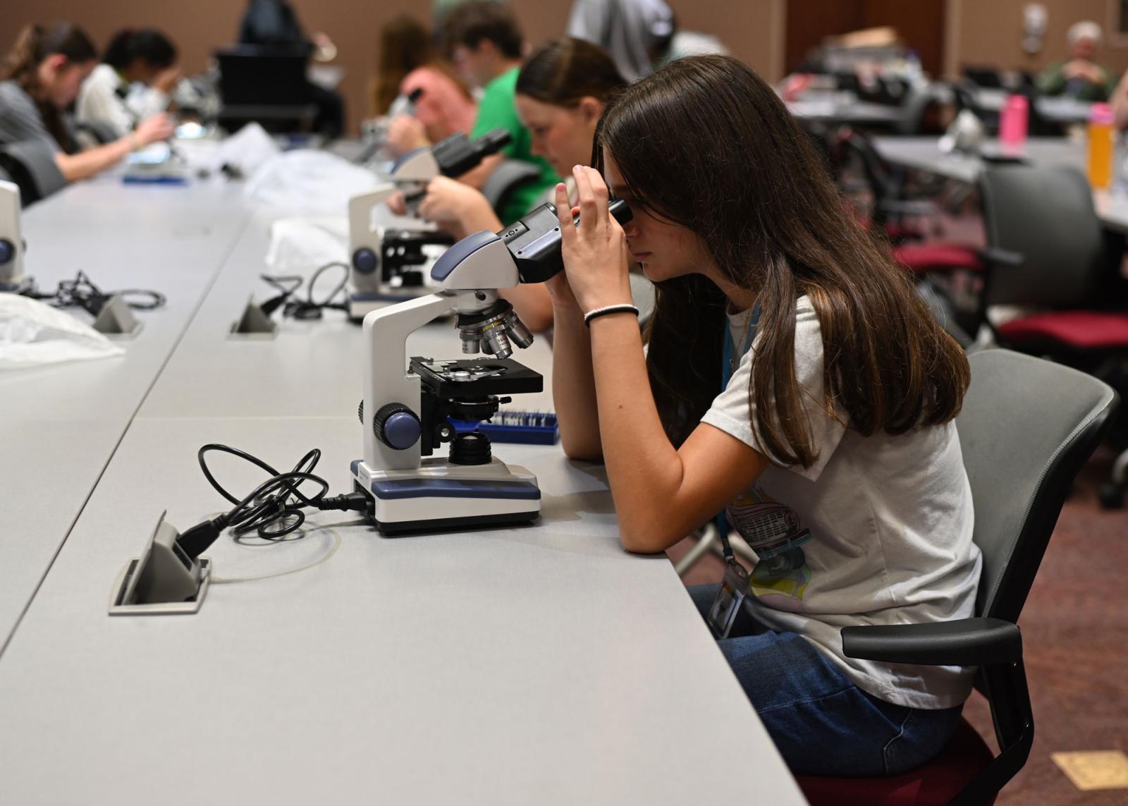High school student looking through a microscope