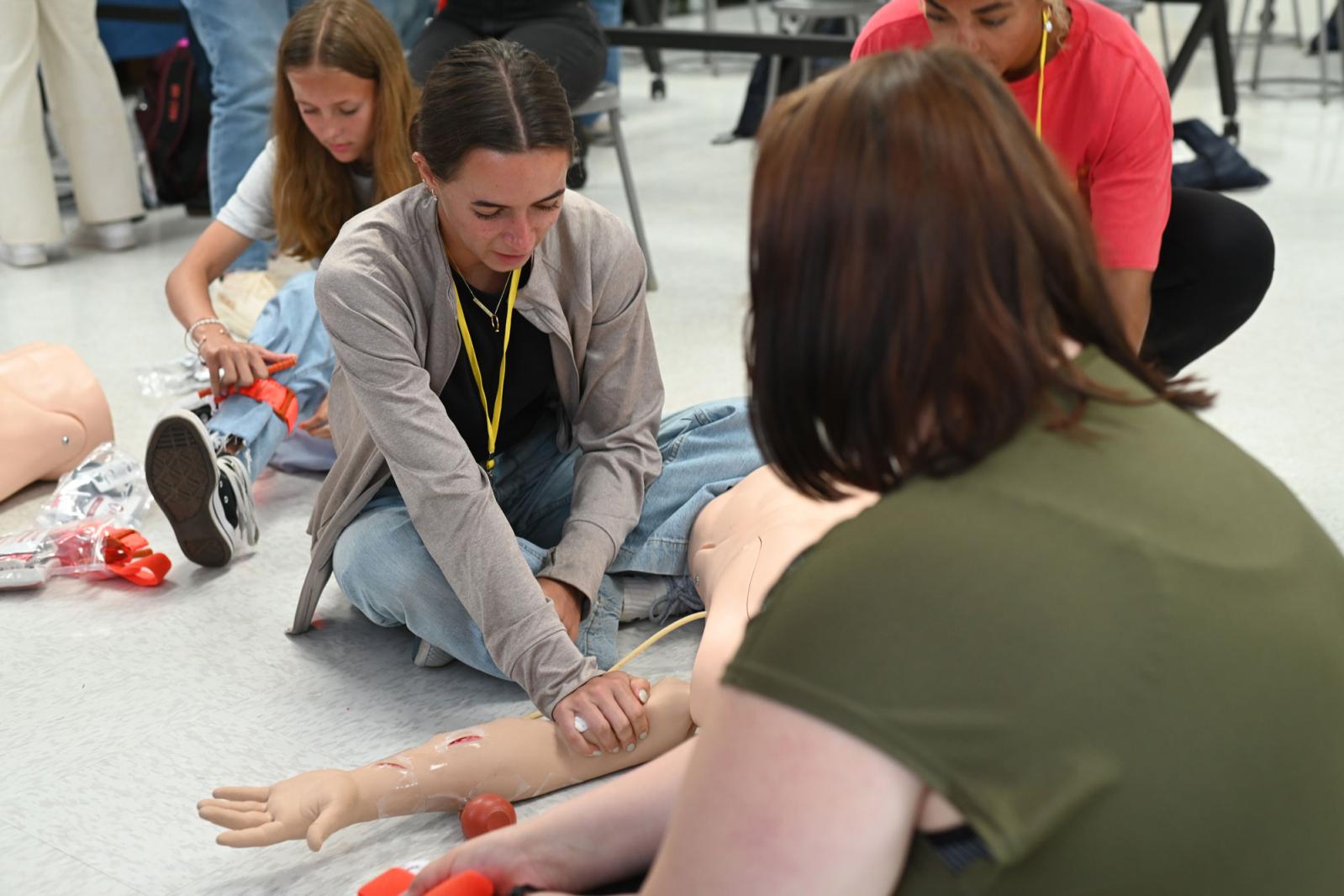 High school student working with a manikin arm during a mini med school event