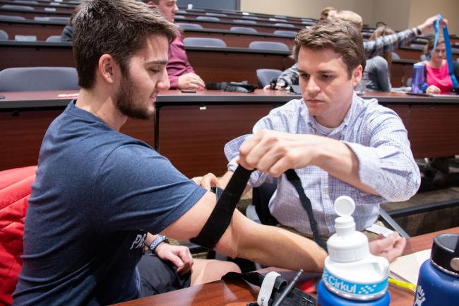 Medical students practice applying a tourniquet.