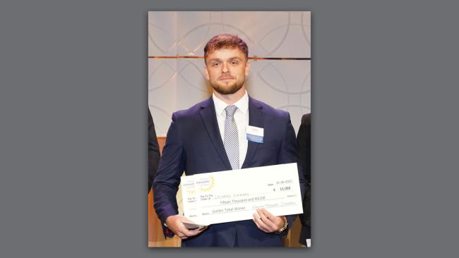 Zach Simmons holding an award check