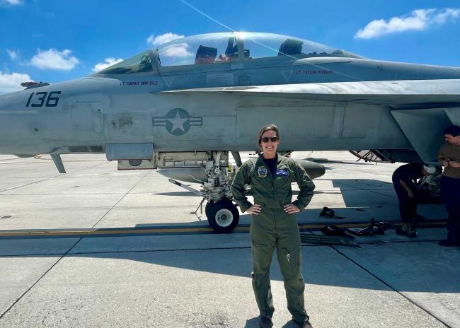 Taylor Rudolph standing in front of a fighter jet with her name under the cockpit