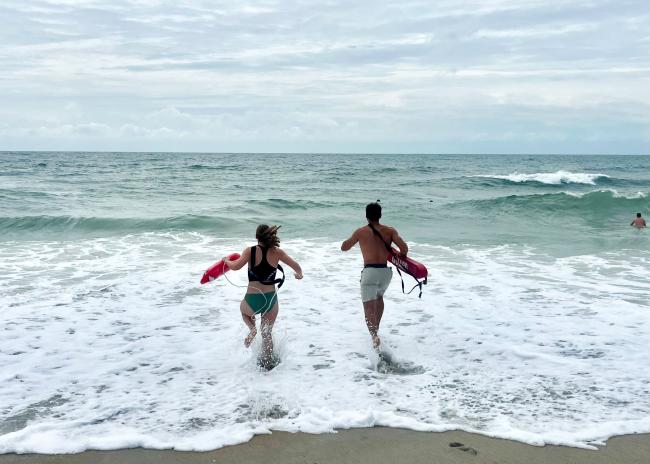 Two lifeguards running out into the ocean to a practice rescue