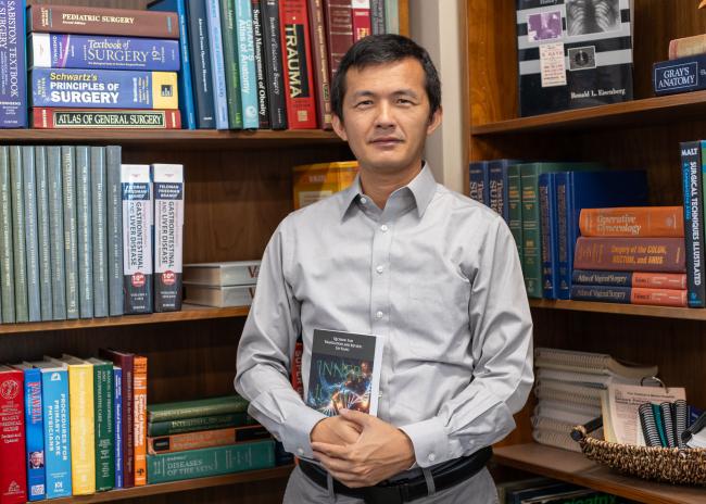 Lin Kang, PhD. holding his book "Inner Logic of Life: Understanding the Origins and Evolution of Life from the Perspective of Complex System"