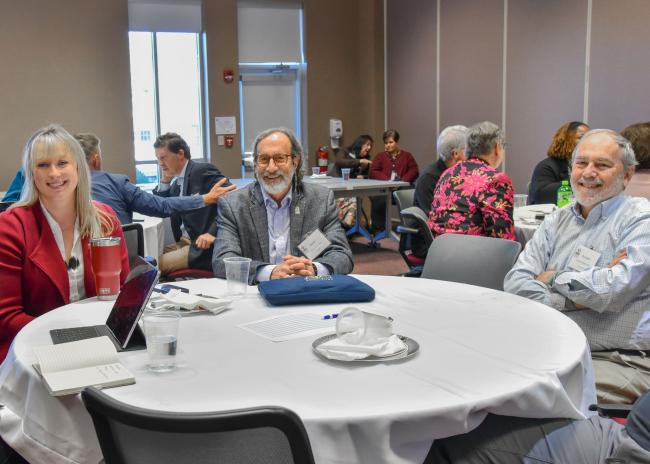 VCOM research retreat attendess sitting around a table smiling