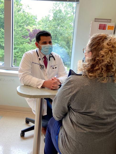 Abdul-Rahman in a mask speaking with patient