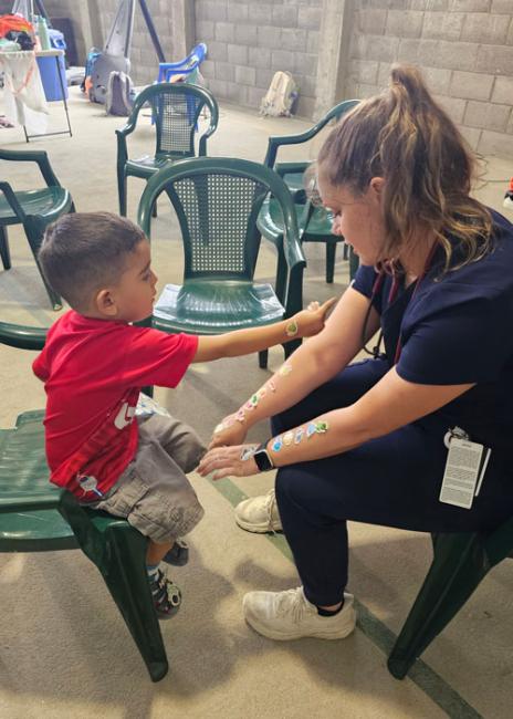 Erin Onken with a young boy putting stickers on her arms during a mission trip 