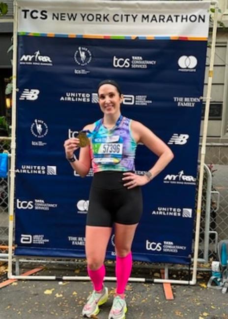 Courtney Pisano holding a medal after a marathon