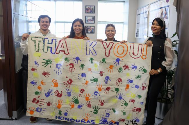 VCOM students and staff display banner made by the children