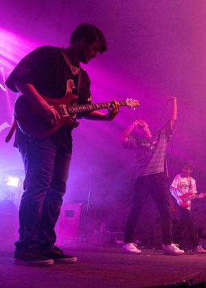 Kade Simar playing guitar on stage with his band