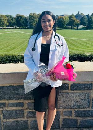 Netra Sivanandan in white coat holding flowers