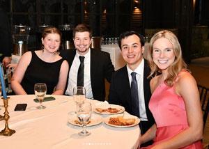 Carlos Jimenez, Jr. at a dinner table smiling with friends