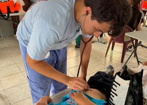 Carlos Jimenez, Jr. using a stethoscope on a child during a mission trip