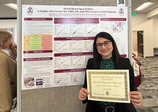 Tanya Kumar holding her award standing in front of her research poster