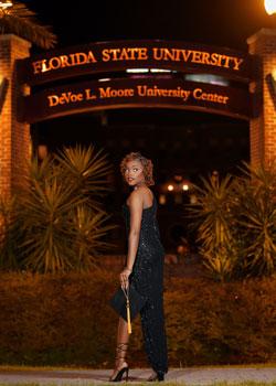 Shelda St. Preux in a dress in front of a Florida State College entrance holding her graduation cap
