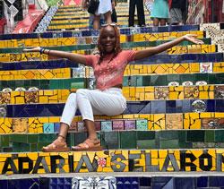 Shelda St. Preux sitting on stairs, arms outstretched and smiling