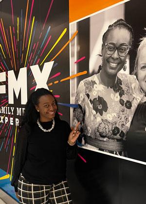 Ariana Martin at a conference pointing to a picture of her used to promote the event