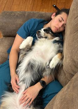 Sydney Gould asleep on a couch with a dog