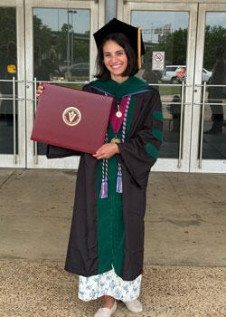 Sydney Gould in cap and gown holding her VCOM diploma