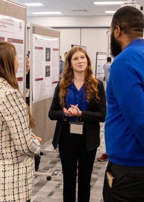 VCOM-Louisiana student talking to two others about her research day poster