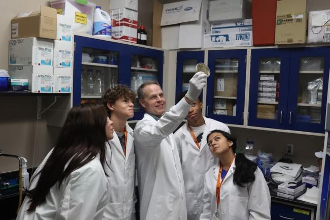 VCOM-Auburn summer enrichment program students in white coats with faculty looking at an object