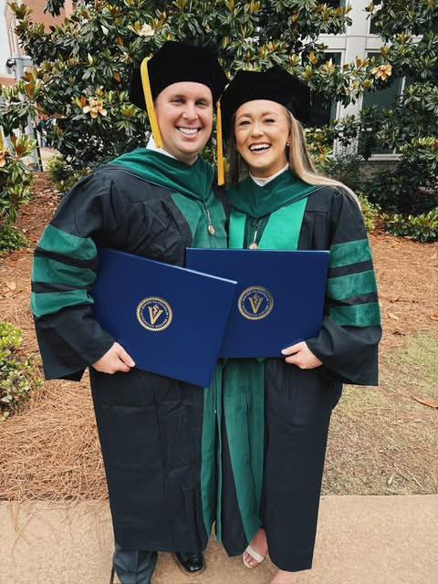 Kristina Alexander holding her diploma with fellow classmate on graduation day