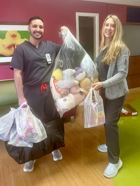 Two medical students holding bags of toys for children in the hospital