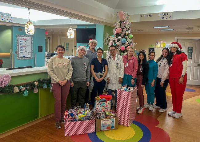 Group picture of members of the PICU toy drive for children with boxes full of toys in front of them