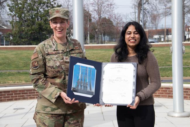 VCOM-Carolinas student holding her commissioning certificate with an Army member