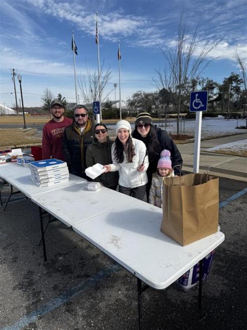 VCOM-Louisiana students standing in front of a portable table smiling